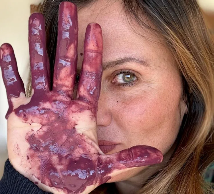 Augusta Bargilli tiene davanti al viso una mano rossa di mosto
